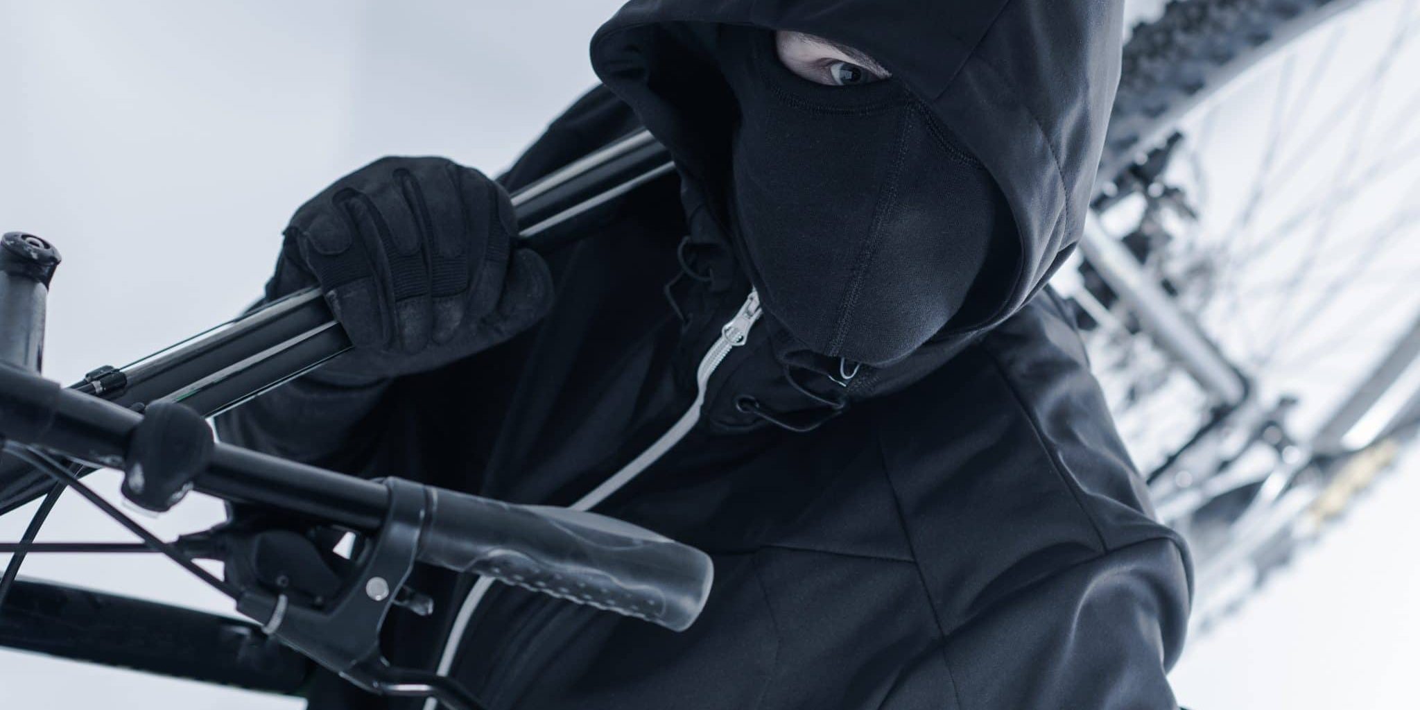 Person in schwarzer Kleidung trägt ein Fahrrad davon