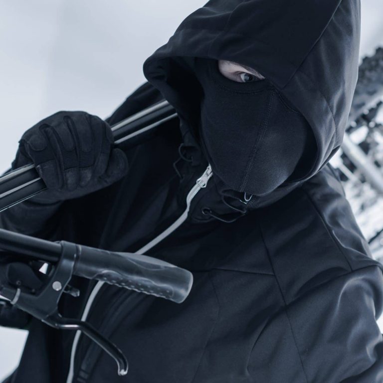 Person in schwarzer Kleidung trägt ein Fahrrad davon