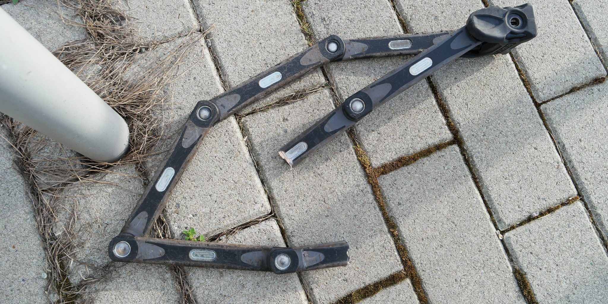 geknacktes Faltfarradschloss neben Metallfahrradständer